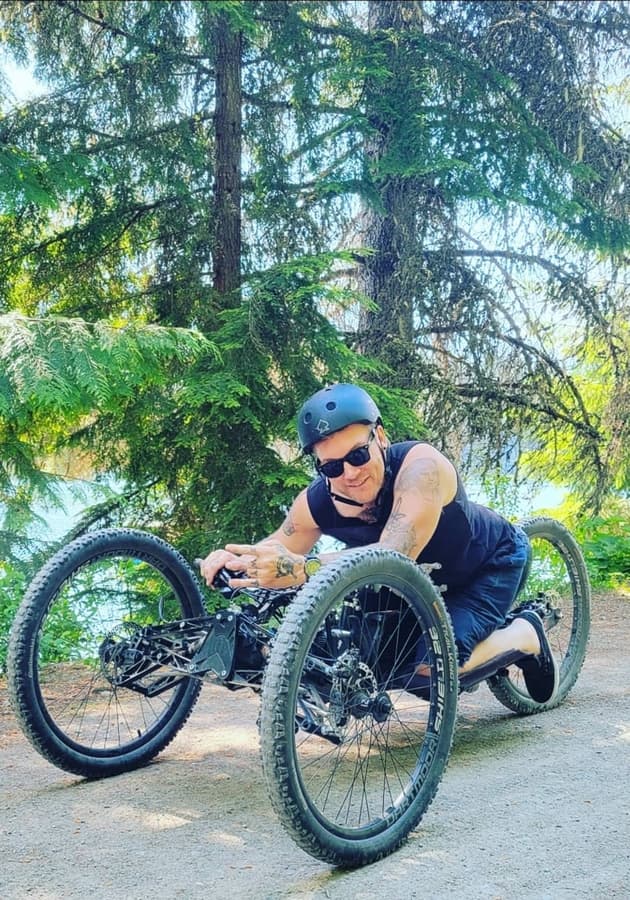 Kevin Brooks riding an adaptive off-road handcycle on a forest trail
