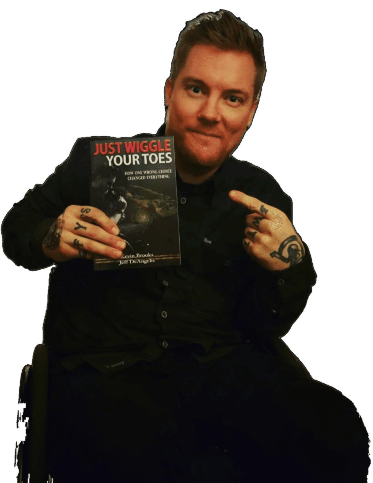Kevin in his wheelchair, holding up his book Just Wiggle Your Toes and pointing at it