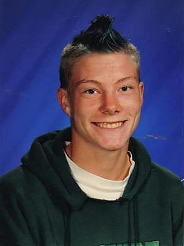 Kevin as a teenager in a school portrait, hair in a mohawk, smiling