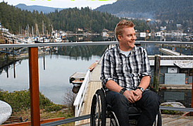 Kevin in his wheelchair on a wooden dock at a British Columbia marina, smiling